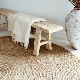 Round natural jute rug styled with a rustic elm bench and cotton throw.