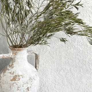 Serene summer interior with handmade ceramics, woven seagrass basket, cotton cushions, and linen pendant lighting in soft natural tones.