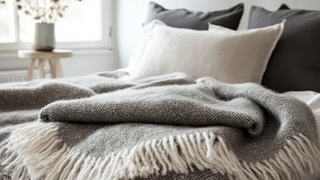 Scandinavian style bedroom with cosy wool blanket draped over the bed.