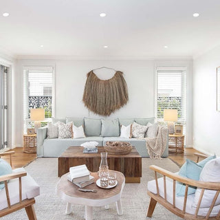 A collection of summer natural homeware essentials, featuring fringed cotton throws, rattan pendant lights, jute rugs, linen bedding and cotton cushions all available from Arkaim Home.