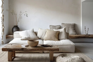 Minimalist, zen-inspired interior featuring a linen sofa, natural scatter cushions, wooden table and rustic ceramic vase.