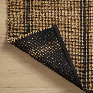 Close up of a hand-braided jute and cotton rug with a textured, two-tone weave in neutral beige and black.
