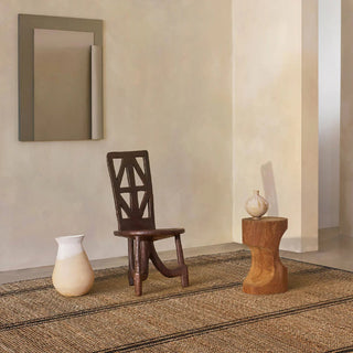 Hand-braided jute and cotton rug with a textured, two-tone weave in soft, neutral beige and black, styled in a modern minimalist interior.