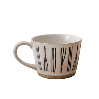 Hand-painted stoneware coffee cup with satin-speckled glaze and graphic motif, styled on a neutral background.