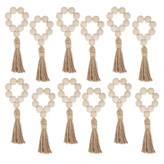 Set of twelve handmade wood bead napkin rings with whitewashed wood and hemp rope tassels, perfect for natural and eco-styled table settings.