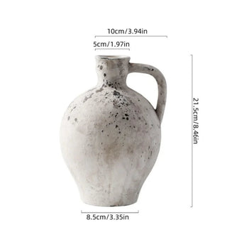 Handmade distressed white ceramic vase. The vase features a classic jug shape with a handle and a distressed finish which exudes rustic charm. It complements contemporary, scandi, rustic or boho home décor. A lovely decorative accessory inspired by nature.