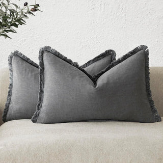 Grey rectangular cotton cushions with fringed trim, styled on a modern beige sofa.