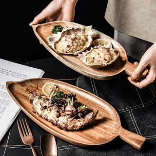 Leaf-shaped serving tray made from natural acacia wood, styled with appetizers.