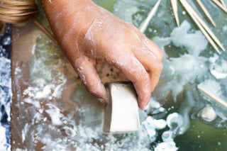 Hand holding a block of pottery clay.