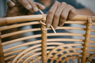 Artisan weaving a basket from natural rattan.