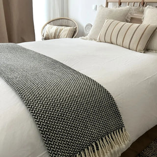 Green and white merino wool blanket draped across a bed, natural soft throw for modern interiors.