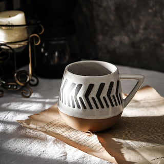 Nordic-inspired handmade clay mug with a white satin-speckled glaze and a black graphic motif, perfect for tea or coffee.