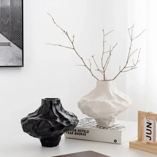 Small black and white asymmetric vases with matte geometric design on a white shelf, minimalist modern home décor accent.