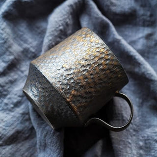 Handmade stoneware mug with textured surface and a bronze metallic glaze, inspired by wabi-sabi aesthetics.