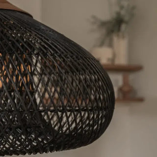 Black handmade rattan and teak pendant light with fish trap shape — artisan ceiling lamp for Wabi Sabi or Boho interiors.