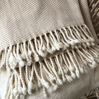 Close-up of beige merino wool weave with hand-tied tassels.