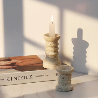 Set of two beige handmade marble candle holders with textured travertine finish, displayed on white background.