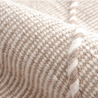 Handwoven beige and white wool rug with geometric kilim pattern and braided fringe for modern, boho and nordic interiors.