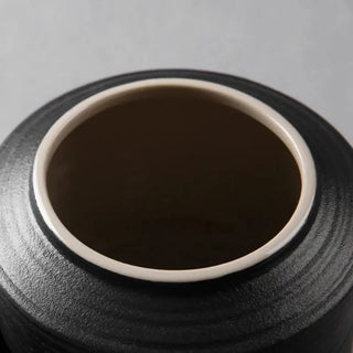 Elegant black ceramic storage jars in various shapes and sizes, featuring a ribbed textured finish and airtight lids. Perfect for storing tea, coffee, sugar, and spices while adding a modern, sophisticated touch to any kitchen countertop.