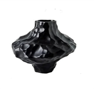 Black ceramic vase with asymmetric sculptural form and matte texture.
