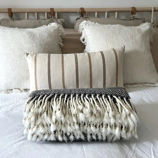 Monochrome merino wool throw styled on a minimalist bed, soft natural blanket for contemporary UK home decor.