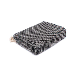 Merino wool throw blanket with a black and white herringbone pattern and a small cream fringe.