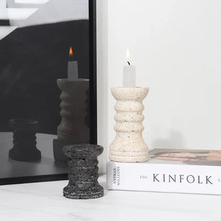 Set of two black and beige handmade marble candle holders with textured travertine finish, displayed with mirror and book