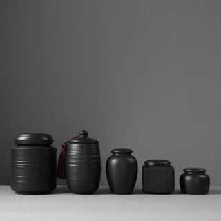 Elegant black ceramic storage jars in various shapes and sizes, featuring a soft textured finish and airtight lids. Perfect for storing tea, coffee, sugar, and spices while adding a modern, sophisticated touch to any kitchen countertop.