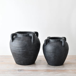Two black ceramic pots with handles and rustic finish.