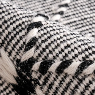 Handwoven black and white wool rug with geometric kilim pattern and braided fringe for modern, boho and nordic interiors.