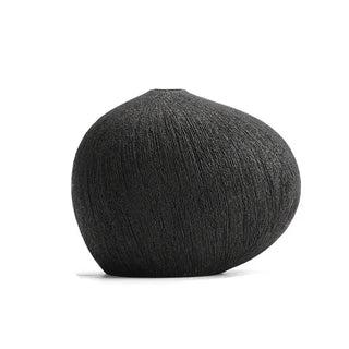 Minimalist black ceramic vase with pebble-inspired shape and textured surface. A sculptural decorative accessory for Japandi, modern, or contemporary interiors.