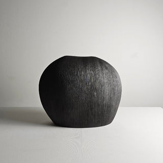 Black textured ceramic vase with a minimalist design, available in two colours that can be styled together. The vase features a creative, organic pebble shape and a black matte finish, perfect for adding a bold, statement look to any modern or contemporary interior.
