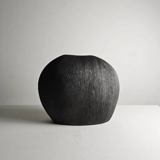 Minimalist black ceramic vase with pebble-inspired shape and textured surface. A sculptural decorative accessory for Japandi, modern, or contemporary interiors.
