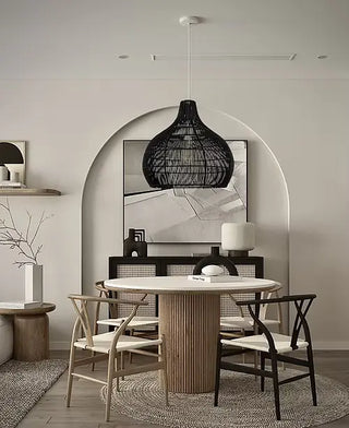 Modern dining room with a round wooden table and chairs, featuring a minimalist black pendant light and abstract art on the wall.