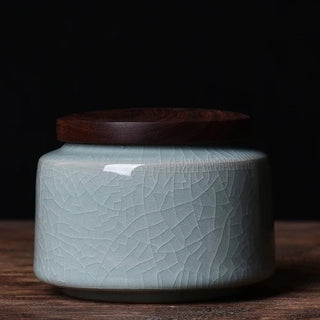 Elegant crackled glaze ceramic storage canister with a dark walnut lid, perfect for kitchen or home organization. Featuring a textured, artisanal design in a soft blue hue, this airtight container is ideal for storing tea, coffee, spices, or small household items. A stylish and functional addition to natural homeware collections.