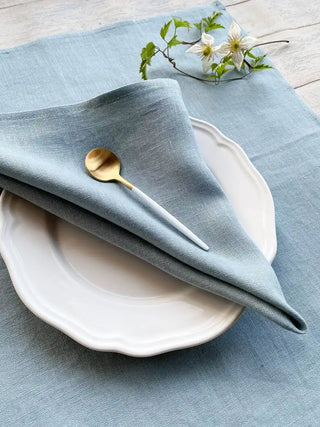 Blue linen napkins set on wooden dining table. 