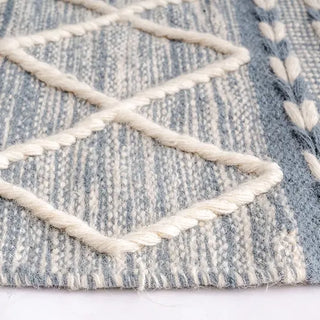 Handwoven blue and white wool rug with geometric kilim pattern and braided fringe for modern, boho and nordic interiors.