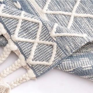 Handwoven blue and white wool rug with geometric kilim pattern and braided fringe for modern, boho and nordic interiors.