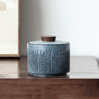 Elegant ceramic tea caddy with a dark walnut lid, perfect for kitchen or home organization. Featuring a textured, artisanal design in a grey blue hue, this airtight container is ideal for storing tea, coffee, spices, or small household items. A stylish and functional kitchen addition to a contemporary, minimalist or Japanese aesthetic.