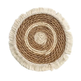 Round boho-style handwoven straw placemats with cotton rope fringe, ideal for rustic and coastal table décor.