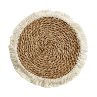 Round boho-style handwoven straw placemats with cotton rope fringe, ideal for rustic and coastal table décor.