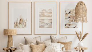 Chic boho styled living room with natural layered cushions, coastal wall prints and rattan lighting.