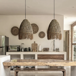 A handwoven rattan and raffia straw pendant light. This natural Cahya pendant lampshade offers a stylish ceiling light, perfect for boho, Scandi, and wabi-sabi home decor. The earthy design enhances any space with its organic charm, making it an ideal choice for natural home decoration and creating a warm, rustic atmosphere. Perfect for adding a unique, sustainable touch to your living room, dining room, or bedroom lighting.