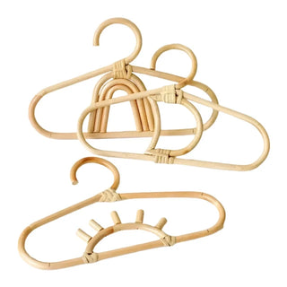 Set of three handmade rattan clothes hangers for kids with woven boho design, nursery-sized and eco-friendly.