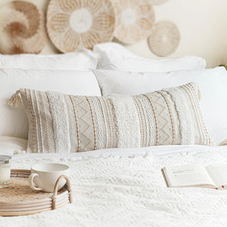 Cosy boho chic styled bedroom with textured rattan wall art, tasselled decorative cushions and round rattan tray.