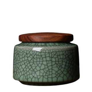 Elegant crackled glaze ceramic storage canister with a dark walnut lid, perfect for kitchen or home organization. Featuring a textured, artisanal design in a soft green hue, this airtight container is ideal for storing tea, coffee, spices, or small household items. A stylish and functional addition to natural homeware collections.