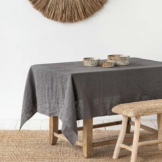 Dark grey linen tablecloth on a rustic on wooden dining table.