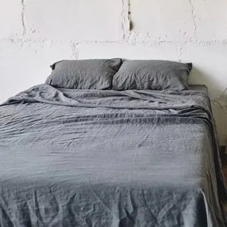 Dark grey pure linen flat sheet and 2 pillowcases set. Available in a range of neutral colours and sizes from Arkaim Home. Natural linen is breathable, textured, and perfect for relaxed year-round comfort. Great for modern, Boho, Scandi, wabi-sabi bedroom interiors.