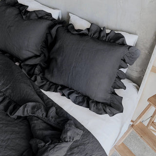 Dark gray ruffled linen pillows and duvet cover on a minimalist bed with a neutral background. Perfect linen bedding set for modern, boho or scandi bedrooms.