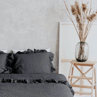 Dark gray ruffled linen pillows and duvet cover on a minimalist bed with a neutral background. Perfect linen bedding set for modern, boho or scandi bedrooms.